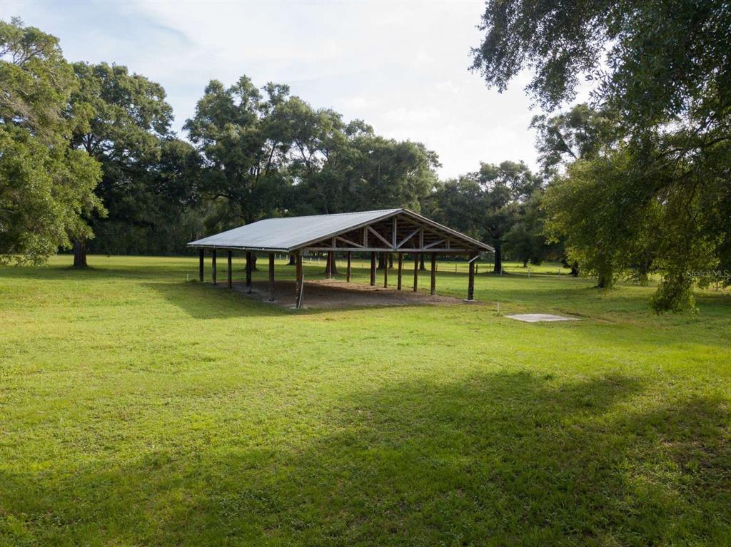 A large, open-sided metal pole barn sits in the middle of a grassy field — Lot 1 NW 94TH AVENUE, ALACHUA, FL