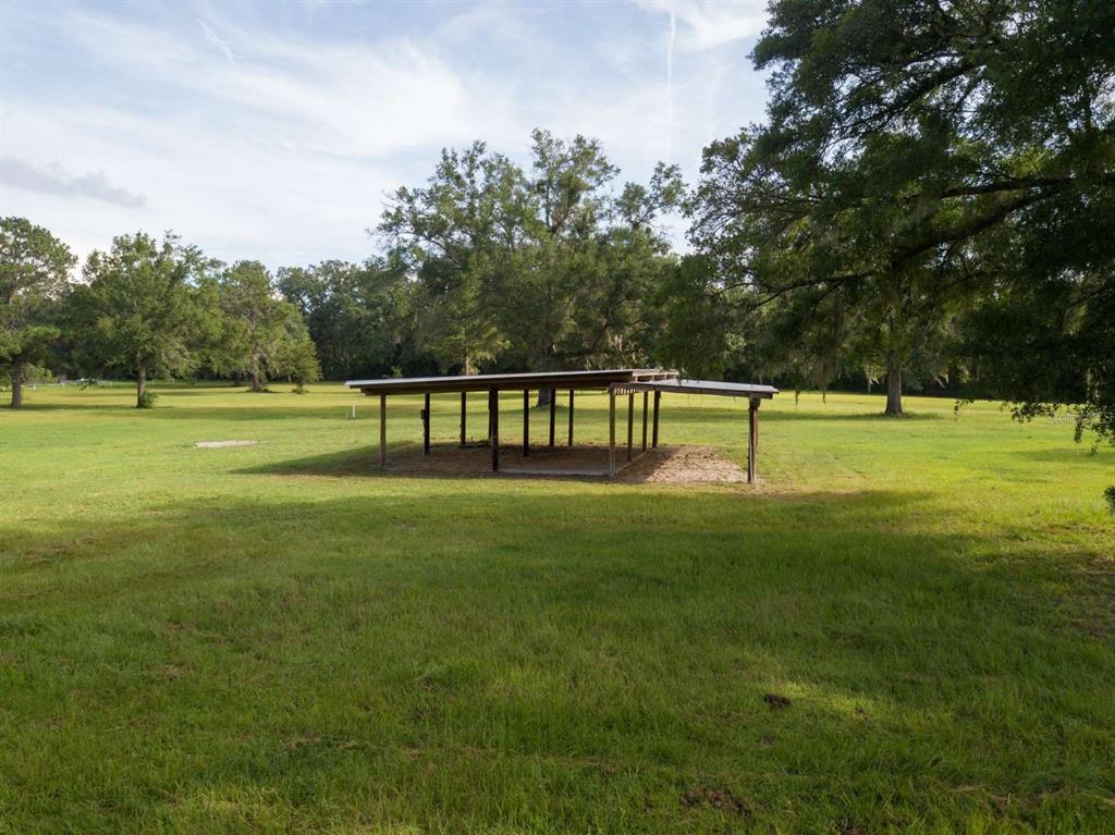 A metal-roofed open-sided shelter stands in the middle of a large, grassy field — Lot 1 NW 94TH AVENUE, ALACHUA, FL