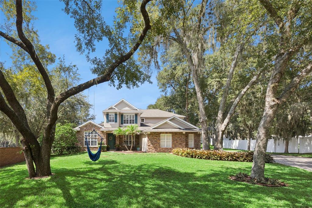 A two-story house with stone siding and a blue hanging chair in the front yard — 32 CLEAR HARBOR COURT, APOPKA, FL