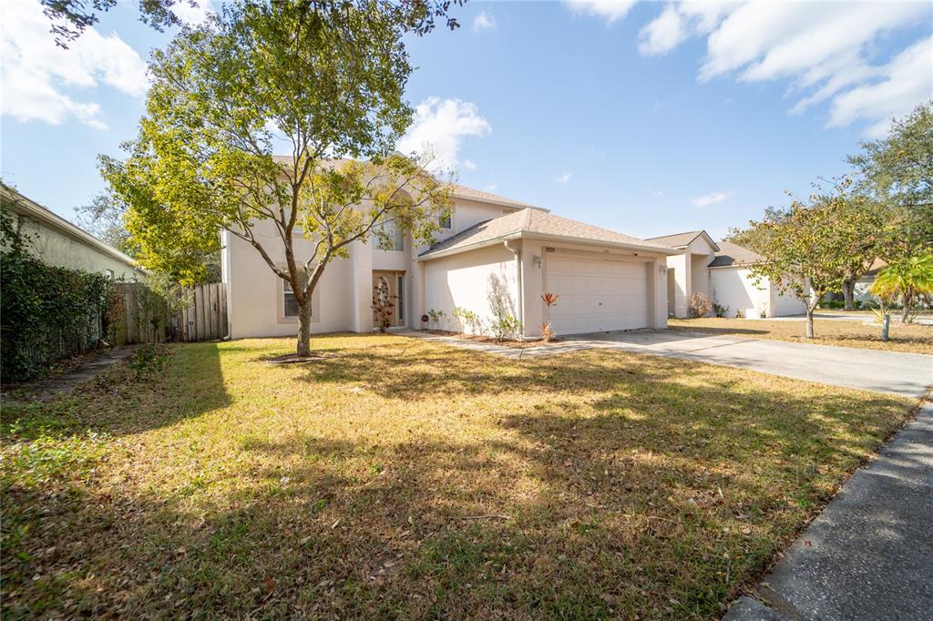 A two-story house with a beige exterior, a two-car garage, and a large front tree — 10529 MARONDA DRIVE, RIVERVIEW, FL