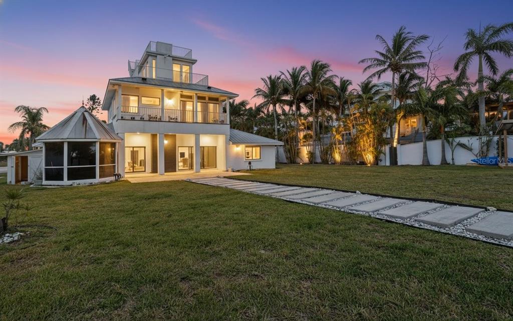A multi-story white house with a metal roof and a stone walkway in the yard — 10218 46TH AVENUE W, BRADENTON, FL