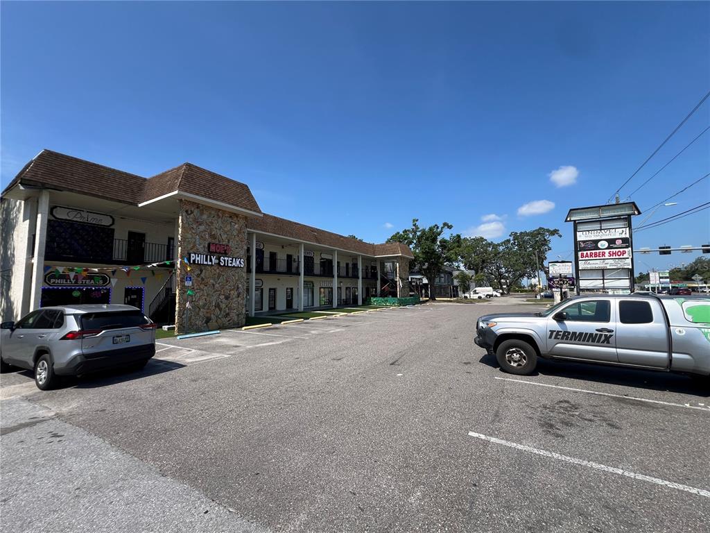 A two-story commercial building with a parking lot and a tall sign for a barber shop — 4819 E BUSCH BOULEVARD, TAMPA, FL