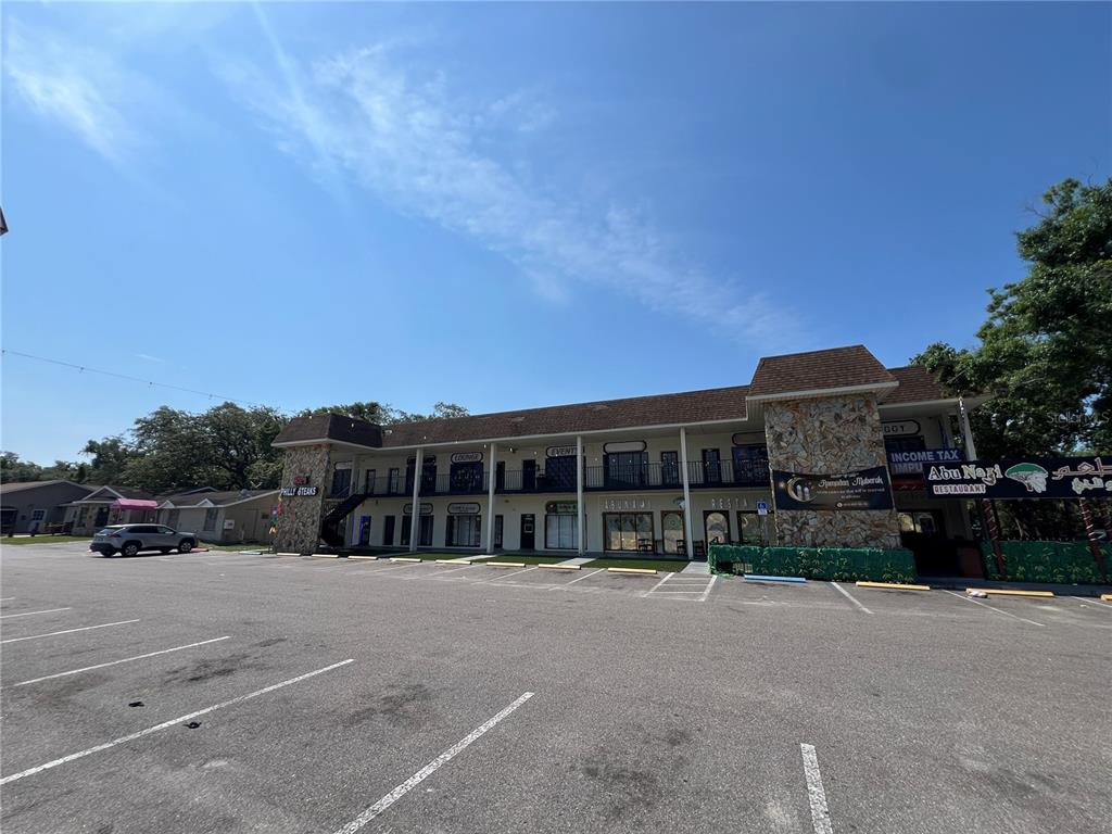 A two-story commercial building with a large parking lot and stone-accented exterior pillars — 4819 E BUSCH BOULEVARD, TAMPA, FL