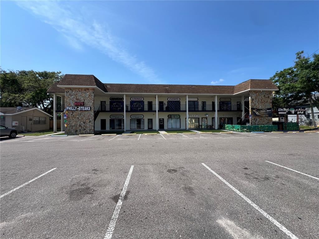 A two-story commercial strip mall with stone accents and a large asphalt parking lot — 4819 E BUSCH BOULEVARD, TAMPA, FL