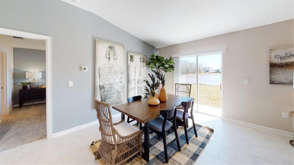 A dining room features a wooden table, mixed seating, wall art, and a sliding glass door — 5204 WORCHESTER DRIVE, KISSIMMEE, FL