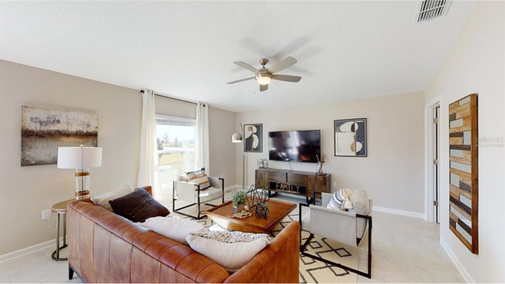 A living room features a leather sofa, two armchairs, a television, and a ceiling fan — 5204 WORCHESTER DRIVE, KISSIMMEE, FL