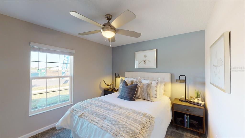A bedroom features a bed with a blue accent pillow, two nightstands, and a ceiling fan — 5204 WORCHESTER DRIVE, KISSIMMEE, FL