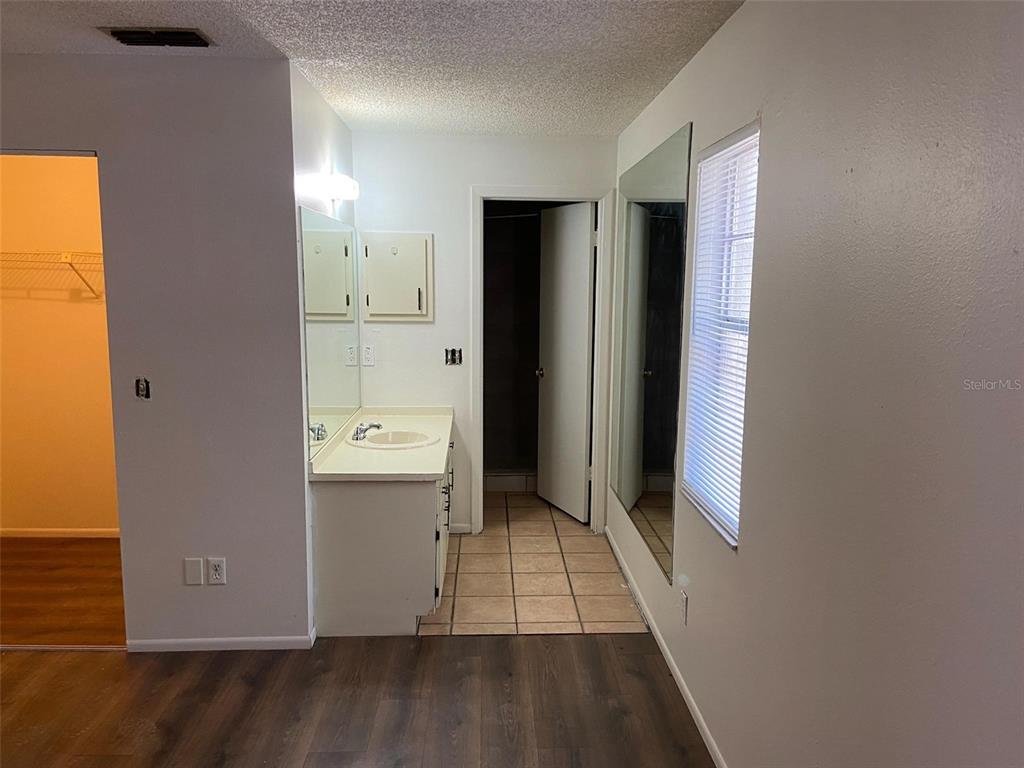 A bathroom vanity with a mirror sits next to a tiled floor and doorway — 3149 HURON AVENUE, OLDSMAR, FL