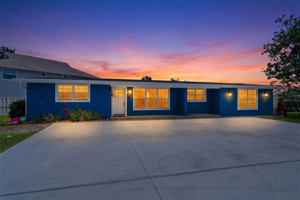 A blue single-story house with a large concrete driveway at sunset — 3325 W SHELL POINT ROAD, RUSKIN, FL