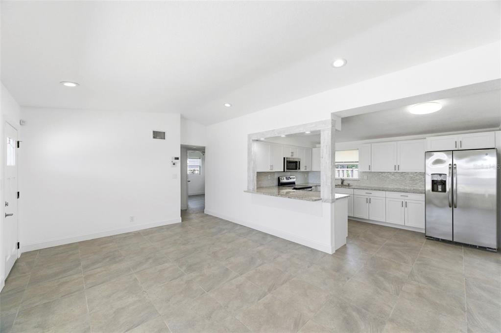 A kitchen with white cabinets and stainless steel appliances opens to a tiled living area — 3325 W SHELL POINT ROAD, RUSKIN, FL