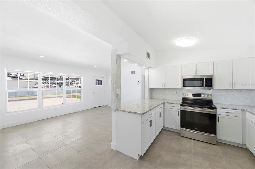 A kitchen with white cabinets and granite countertops opens into a living area with tile floors — 3325 W SHELL POINT ROAD, RUSKIN, FL