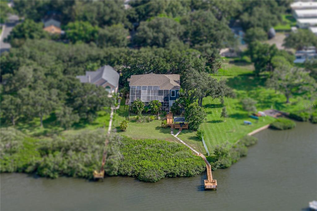 A two-story dark blue house with a three-car garage and mature trees in front — 3484 SHORE DRIVE, SAFETY HARBOR, FL