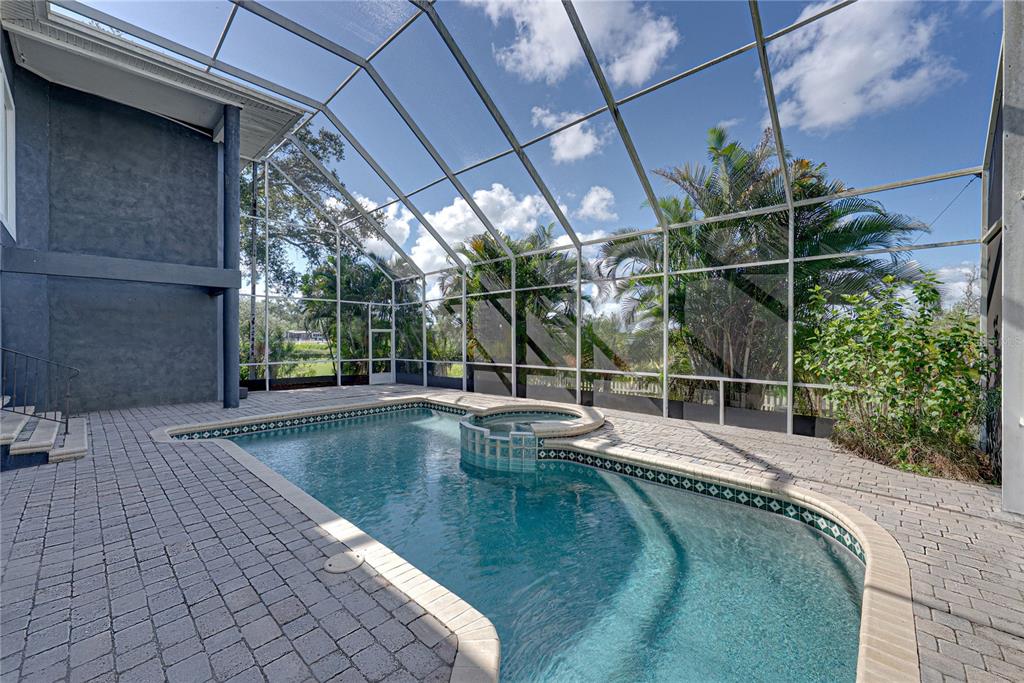 A foyer features a staircase with a glass railing, blue walls, and a marble console table — 3484 SHORE DRIVE, SAFETY HARBOR, FL