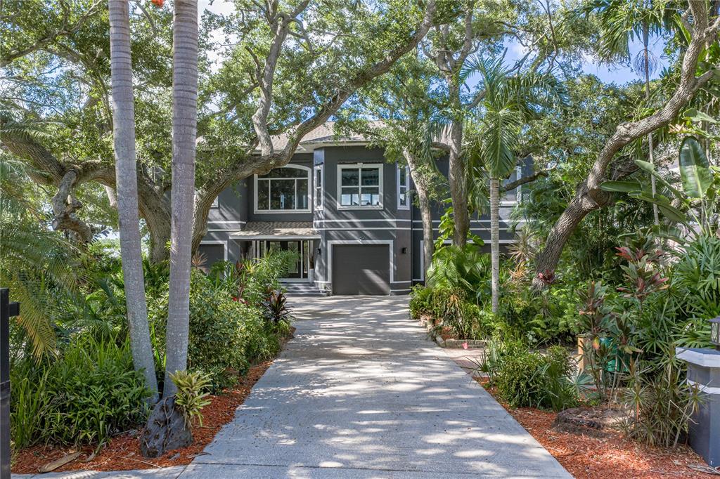 A modern entryway features a glass-railed staircase, wood-look tile flooring, and a marble console table — 3484 SHORE DRIVE, SAFETY HARBOR, FL