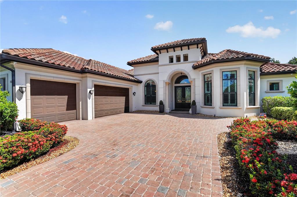 A single-story Mediterranean-style house with a brick paver driveway and a three-car garage — 11810 RIVER SHORES TRAIL, PARRISH, FL