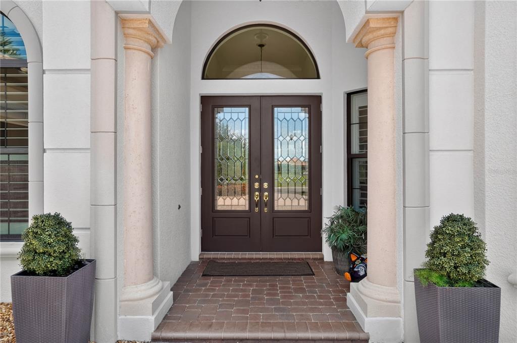 A front entryway features double glass-paneled doors, arched transom window, and two decorative stone columns — 11810 RIVER SHORES TRAIL, PARRISH, FL