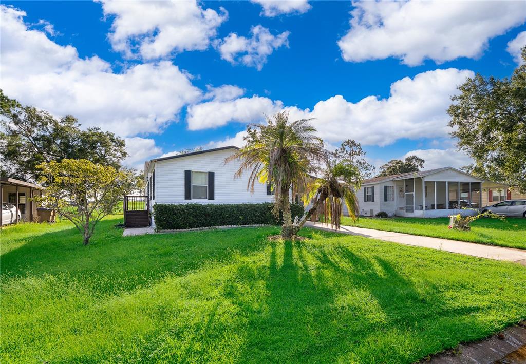 A white single-story manufactured home features a palm tree in the front yard — 2721 DOWNING DRIVE, KISSIMMEE, FL