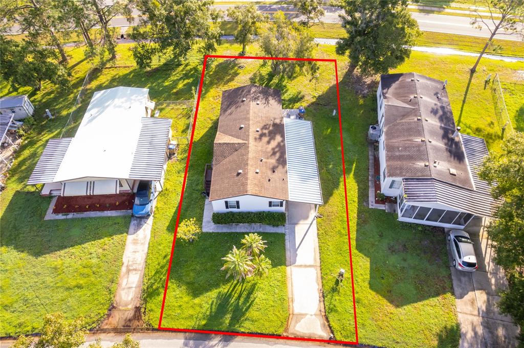 An aerial view shows a single-story house with a brown roof and a concrete driveway — 2721 DOWNING DRIVE, KISSIMMEE, FL