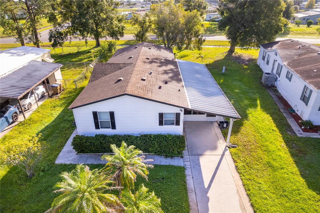 An aerial view of a white single-story house with a metal carport and shingled roof — 2721 DOWNING DRIVE, KISSIMMEE, FL