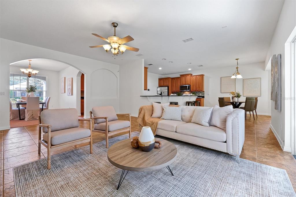 A living room with a sofa, two armchairs, a coffee table, and an open kitchen — 554 PALIO COURT, OCOEE, FL