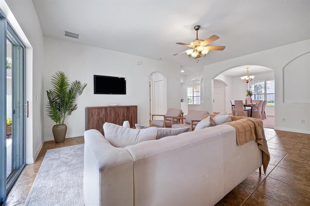 A living room with a white sofa, wood console, and tile flooring leads to a dining area — 554 PALIO COURT, OCOEE, FL