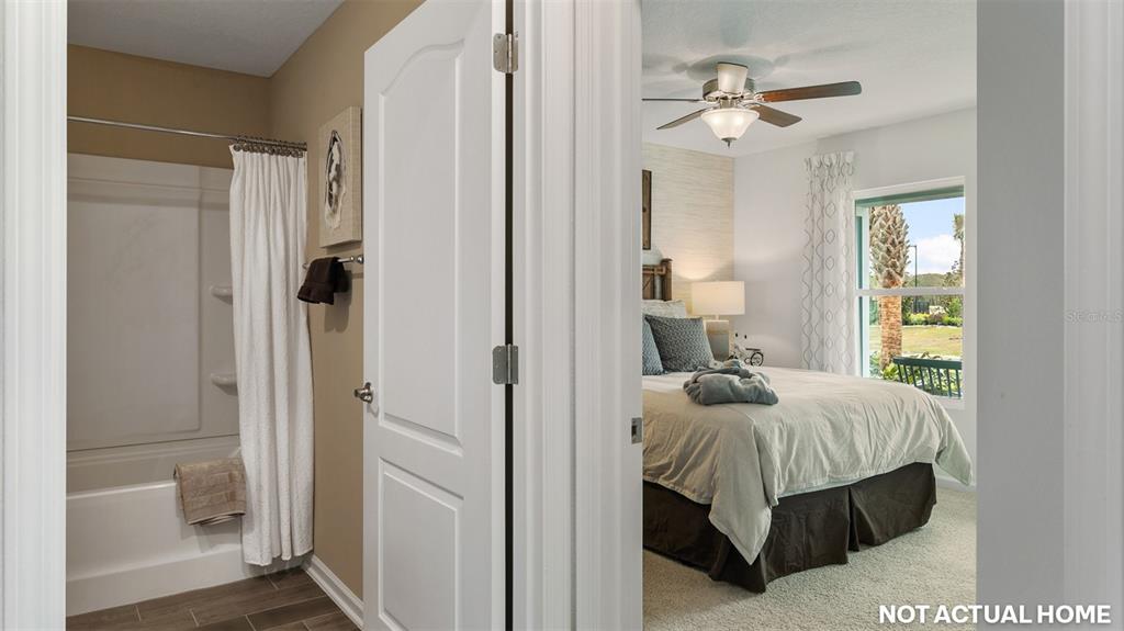 A bathroom with a shower-tub combo is visible next to a bedroom with a ceiling fan — 50 HARDWOOD TRAIL, PALM COAST, FL