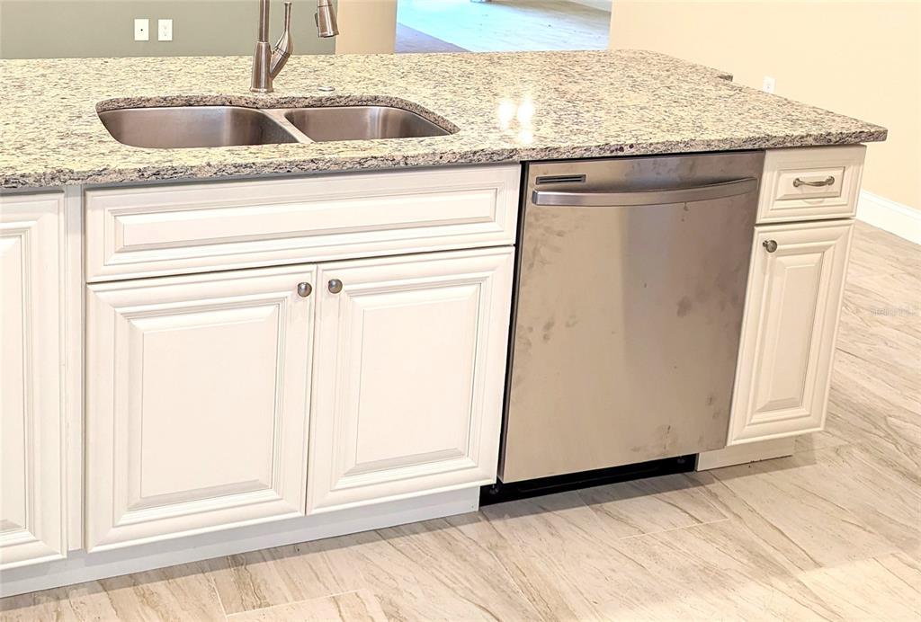 A kitchen island features a granite countertop, stainless steel sink, and a stainless steel dishwasher — 104 ROBERTS AVENUE, MULBERRY, FL