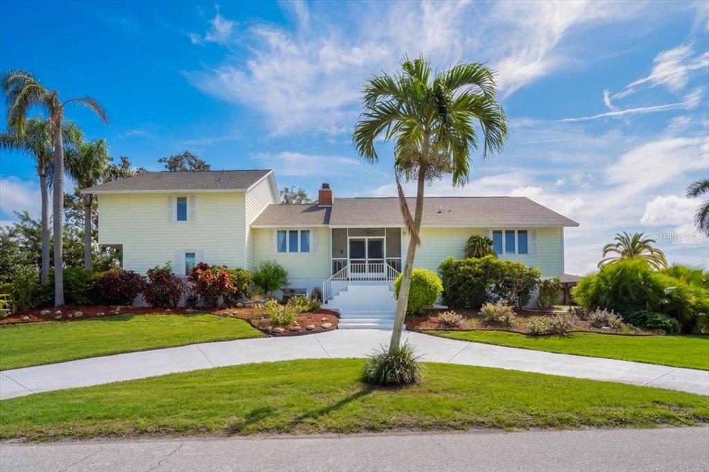 A two-story, light yellow house with a palm tree in the front yard — 2407 PALMA SOLA BOULEVARD, BRADENTON, FL