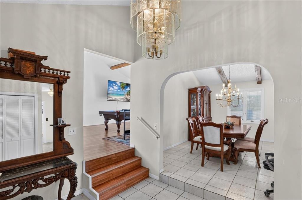 An entryway with a chandelier leads to a dining room and a room with a pool table — 2407 PALMA SOLA BOULEVARD, BRADENTON, FL