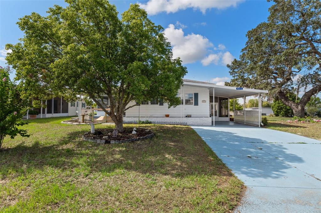 A white mobile home features a large shade tree and a light blue painted driveway — 9075 HIGHPOINT BOULEVARD, BROOKSVILLE, FL