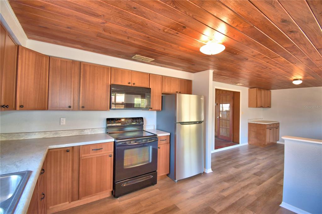 A kitchen features wood-paneled ceilings, wooden cabinetry, stainless steel appliances, and light-colored countertops — 352 E HWY 630 E, FROSTPROOF, FL