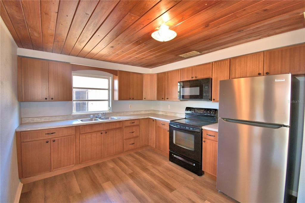 A living room features wood-paneled ceilings, light-colored walls, wood-look flooring, and a brick fireplace — 352 E HWY 630 E, FROSTPROOF, FL