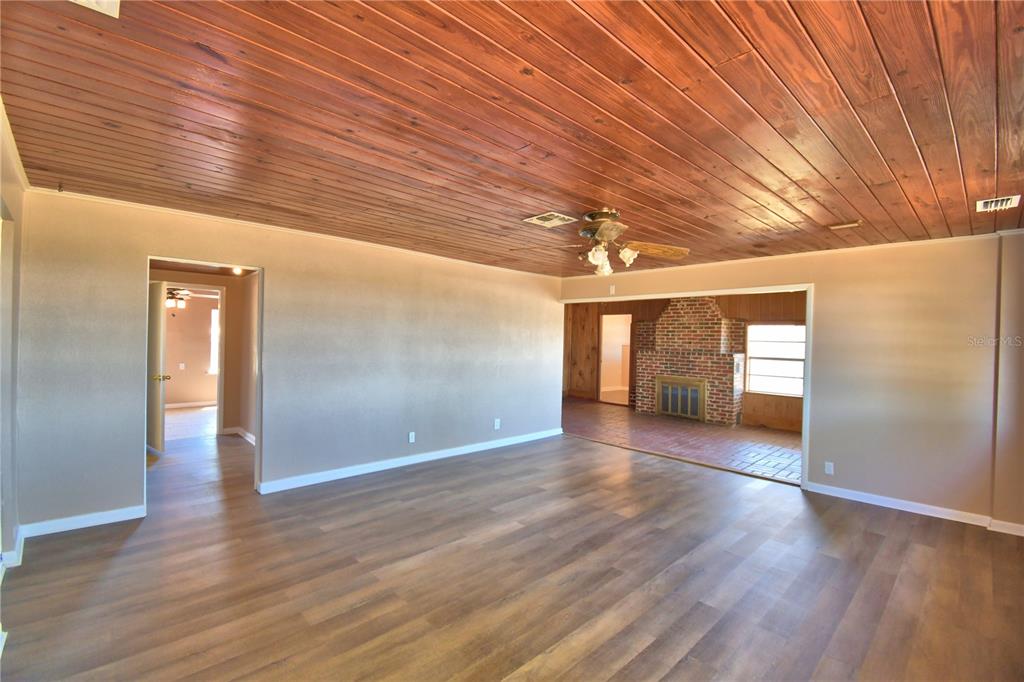 A living room features a wood-paneled ceiling, light brown walls, and a brick fireplace — 352 E HWY 630 E, FROSTPROOF, FL
