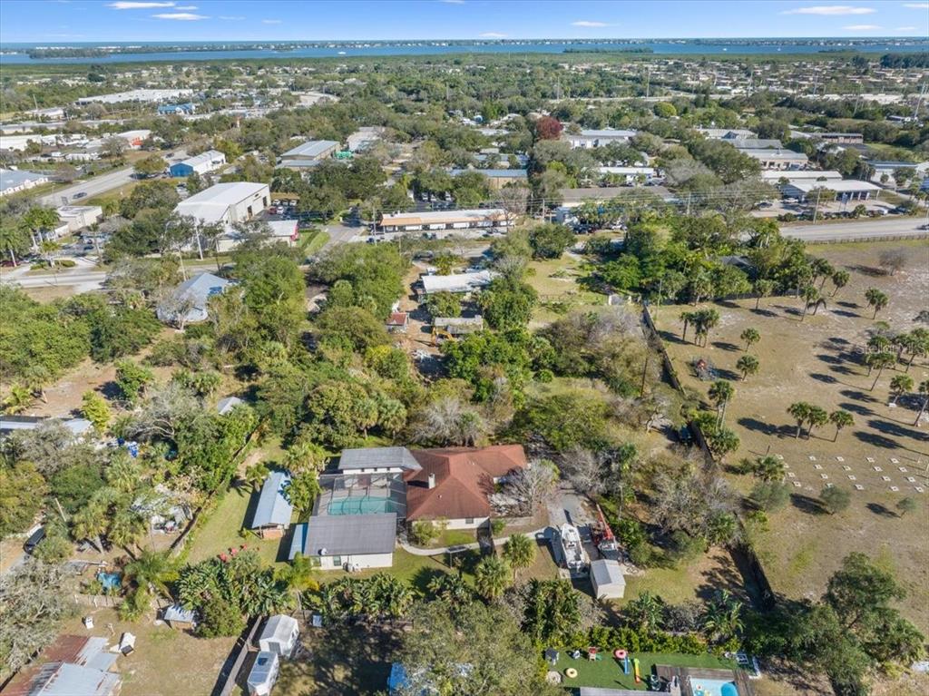 An aerial view shows a residential house with a pool cage and surrounding wooded property — 281 OLD DIXIE HIGHWAY, VERO BEACH, FL