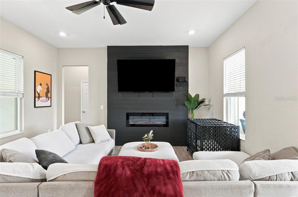 A living room features a black shiplap accent wall with a fireplace and mounted television — 795 CROSSTOWER DRIVE, WINTER HAVEN, FL