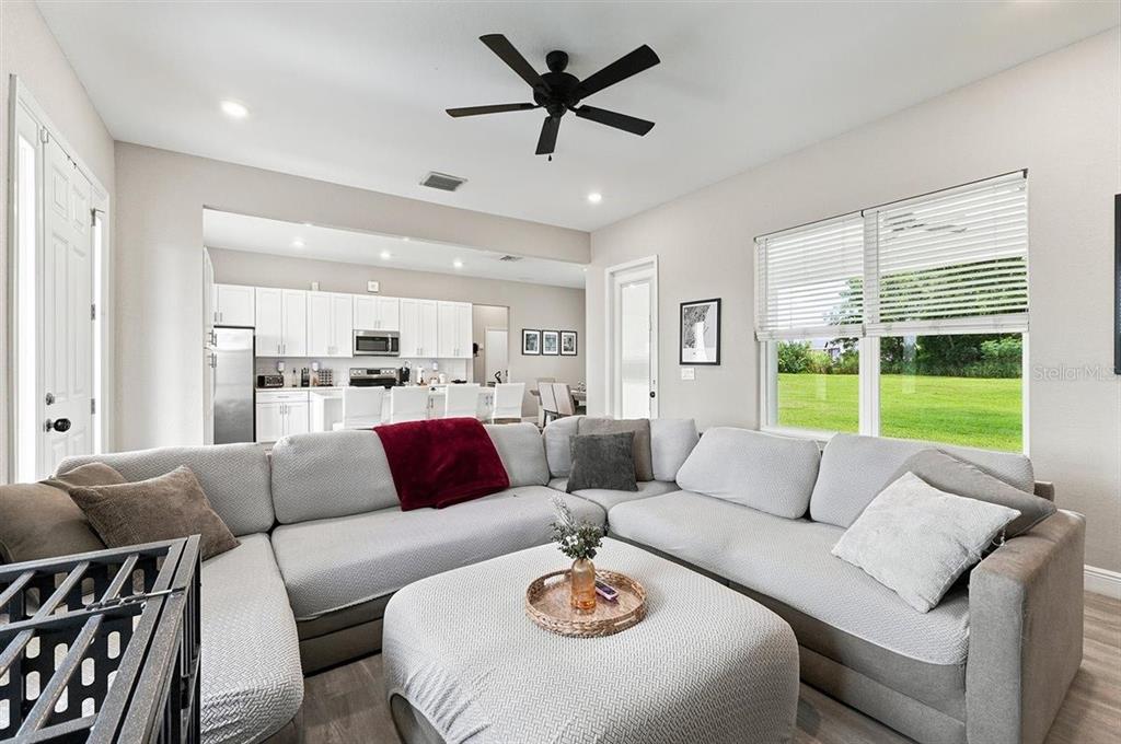 A living room with a large gray sectional sofa, a central ottoman, and an open kitchen — 795 CROSSTOWER DRIVE, WINTER HAVEN, FL