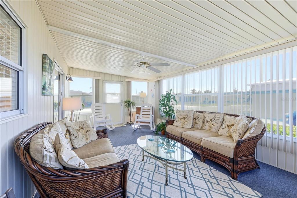 A sunroom features wicker furniture, a glass coffee table, and vertical blinds on windows — 1107 44TH AVENUE DRIVE E, ELLENTON, FL
