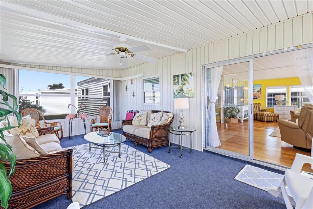 A sunroom with blue carpeting, wicker furniture, and a sliding glass door to the interior — 1107 44TH AVENUE DRIVE E, ELLENTON, FL