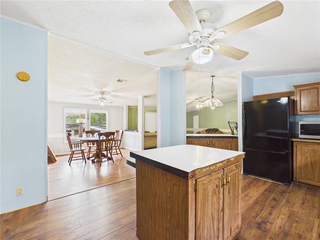 A kitchen with a wooden island and black refrigerator opens into a dining area — 7085 S RHODER POINT, LECANTO, FL
