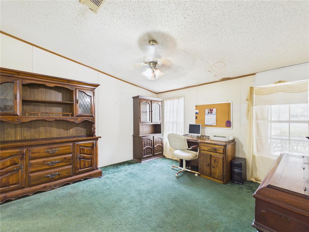 A home office features green carpeting, wood furniture, a desk, and a ceiling fan — 7085 S RHODER POINT, LECANTO, FL