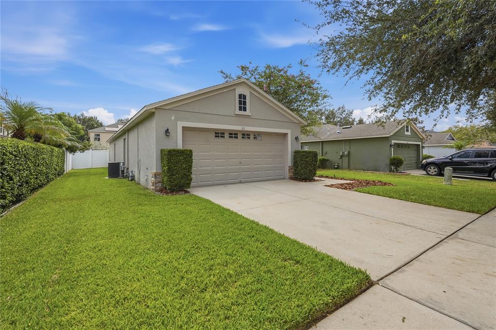 A single-story house exterior features a two-car garage, a concrete driveway, and a green lawn — 311 WESTCHESTER HILLS LANE, VALRICO, FL