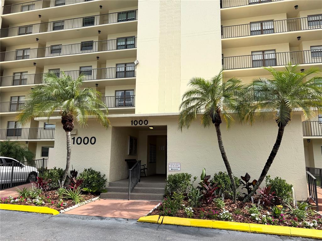 A multi-story apartment building with balconies and a parking lot in front — 1000 COVE CAY DRIVE UNIT 4D, CLEARWATER, FL