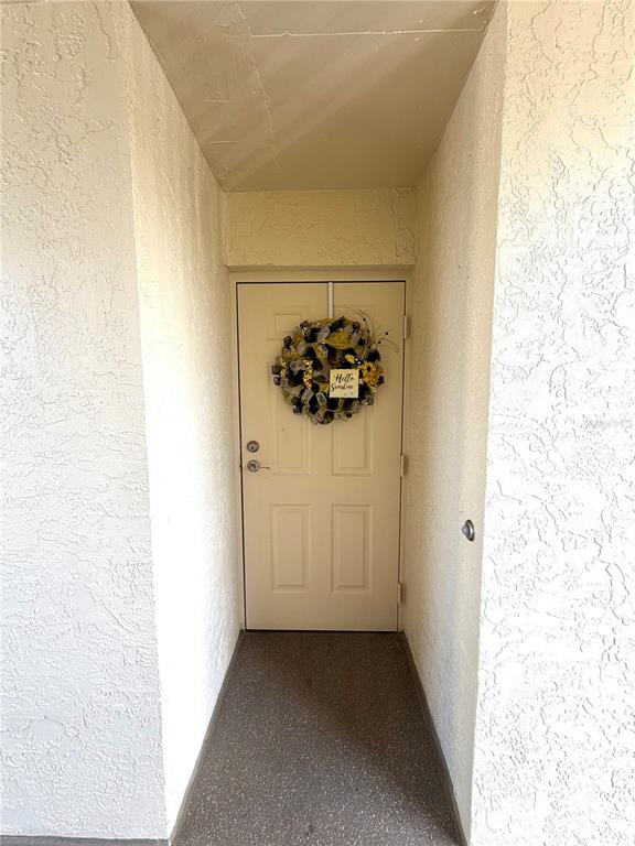 The exterior of a multi-story apartment building features balconies, palm trees, and a ground-level entrance — 1000 COVE CAY DRIVE UNIT 4D, CLEARWATER, FL