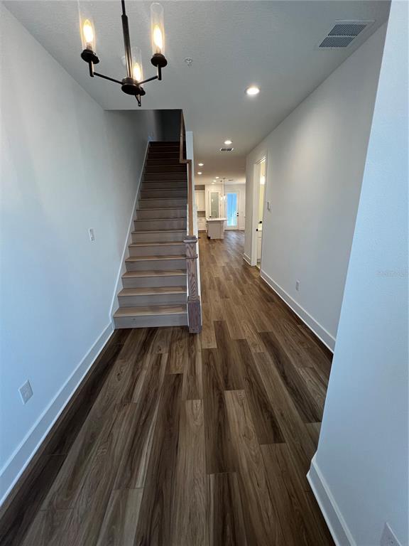 An entryway features wood-look flooring, a staircase with a wooden railing, and a modern chandelier — 1819 PINECLIFF DRIVE, APOPKA, FL