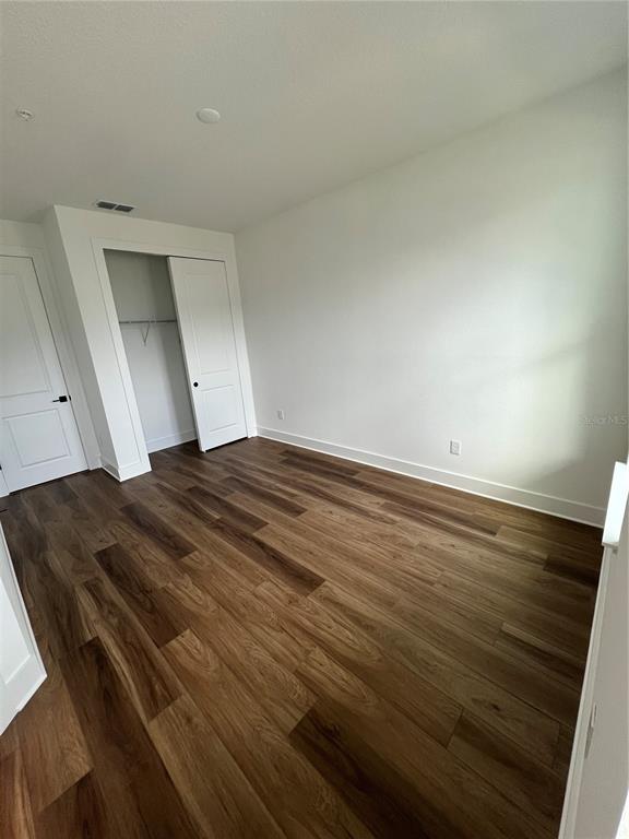 An empty bedroom features wood-look flooring, white walls, and a closet with white doors — 1819 PINECLIFF DRIVE, APOPKA, FL