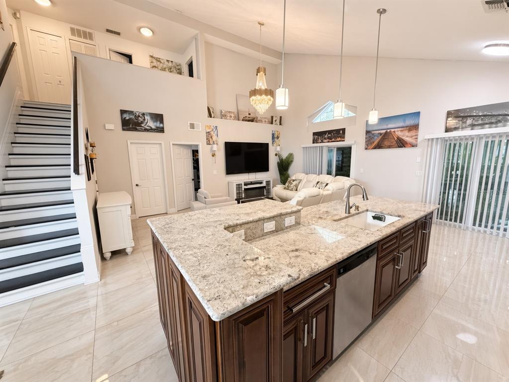 A kitchen island with granite countertops sits in an open-concept living area with high ceilings — 3010 STILLWATER DRIVE, KISSIMMEE, FL