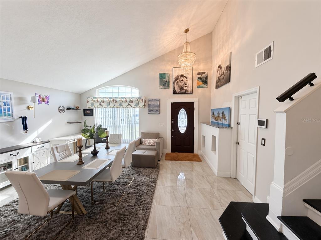 A dining area with tile floors, a vaulted ceiling, and a chandelier near the entrance — 3010 STILLWATER DRIVE, KISSIMMEE, FL