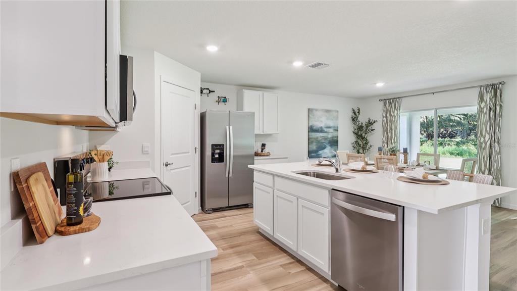 A modern kitchen features white cabinets, stainless steel appliances, and a large central island — 13042 SW 88TH COURT, OCALA, FL