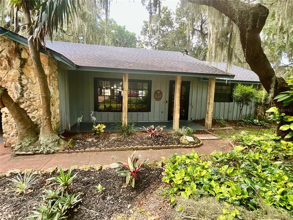 A single-story house with a stone facade, vertical siding, and a covered front porch — 2430 W COUNTY ROAD 44, EUSTIS, FL