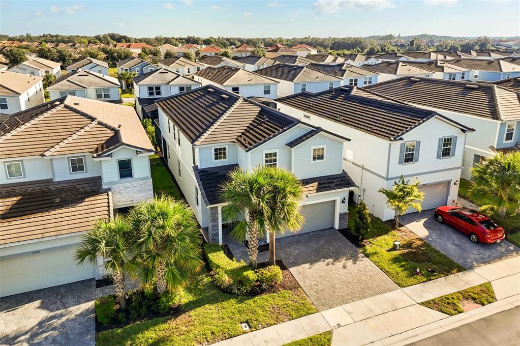 An aerial view shows suburban houses with dark tiled roofs and paved driveways — 7352 OAKMOSS LOOP, DAVENPORT, FL